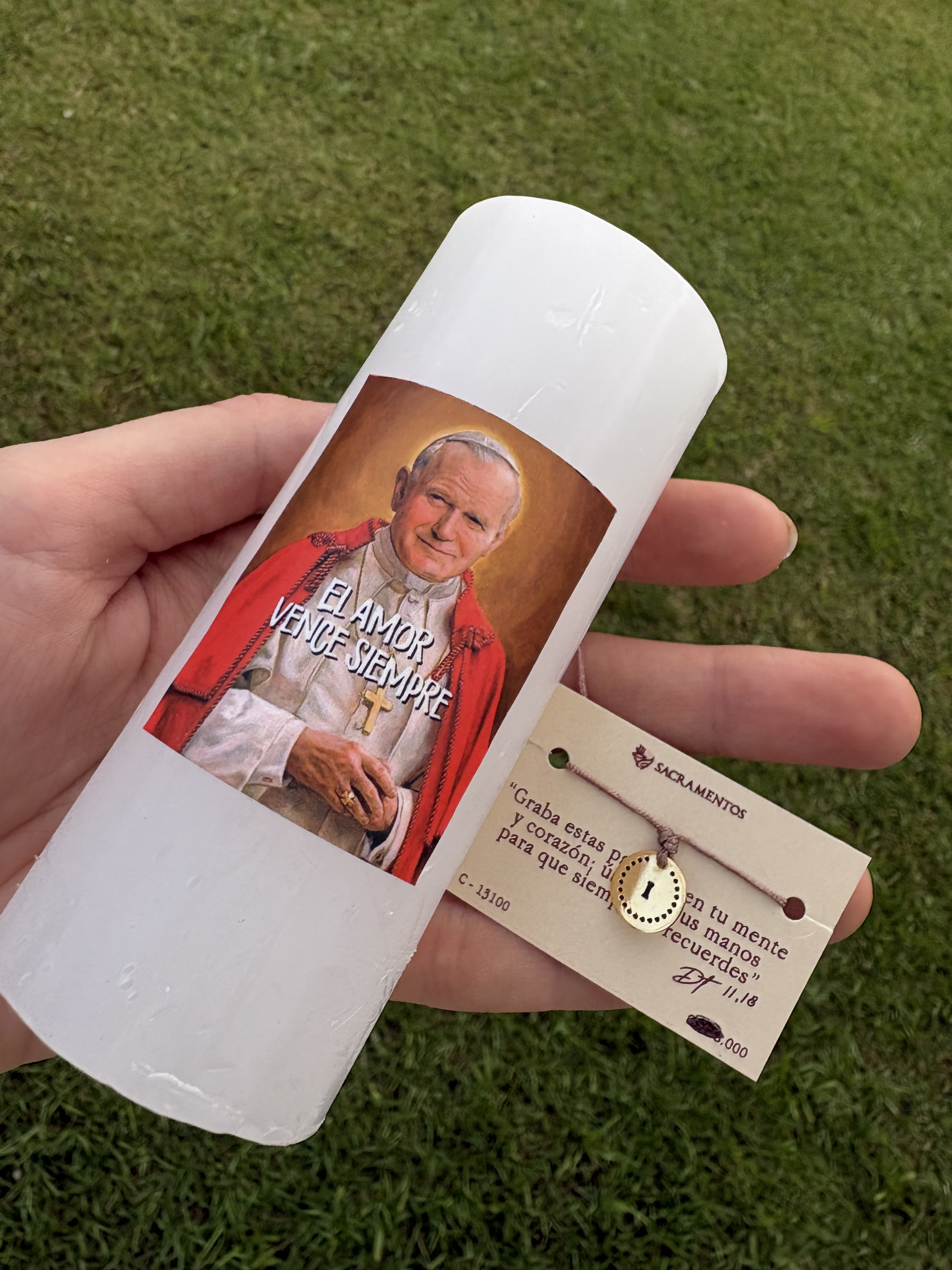 Vela encendida con inscripción de San Juan Pablo II - El Amor Vence Siempre